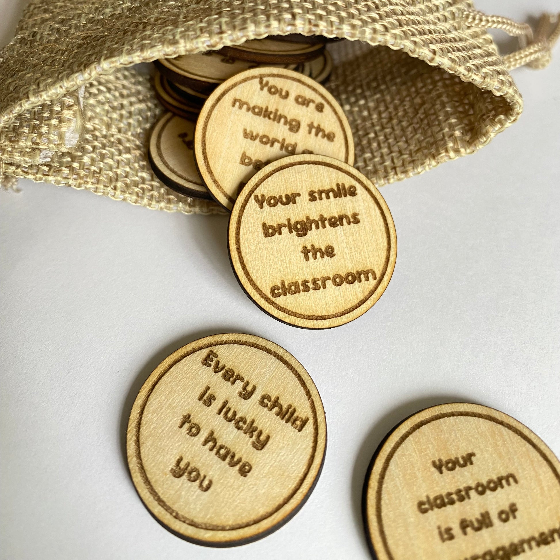 Wooden teacher keepsake affirmation coins with uplifting words of appreciation, perfect for teachers and teaching assistants.